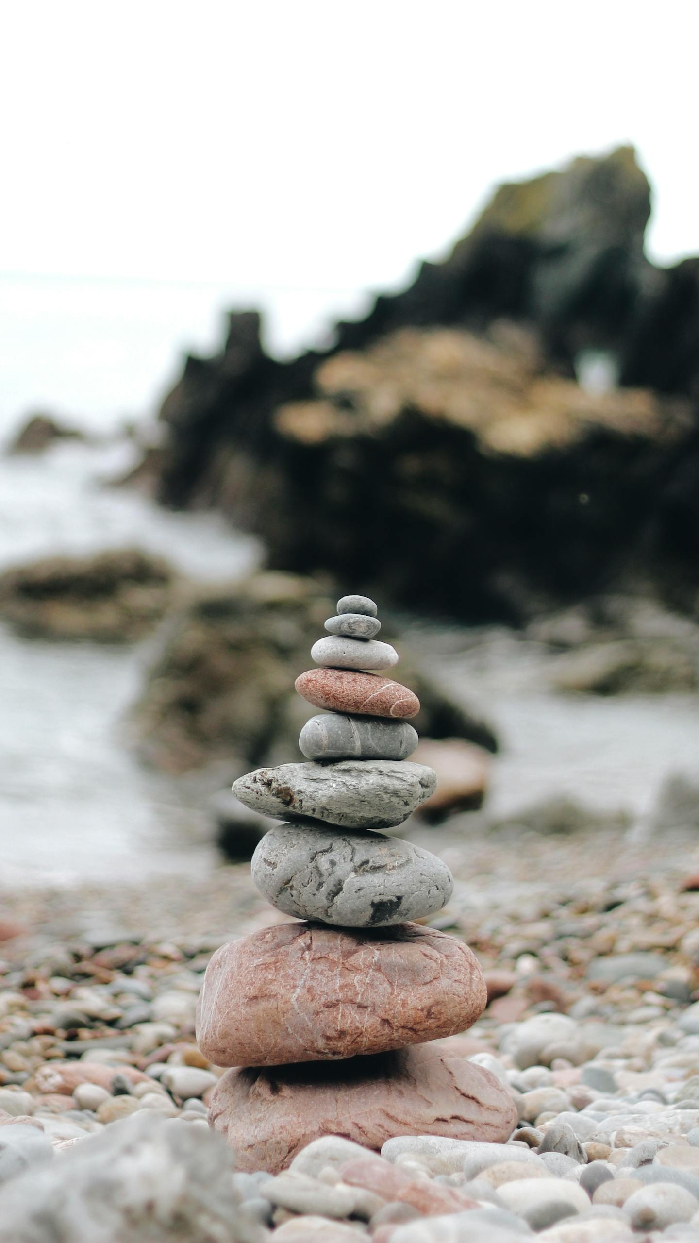 Tranquil stacked stones on a rocky beach, symbolizing balance and calm.