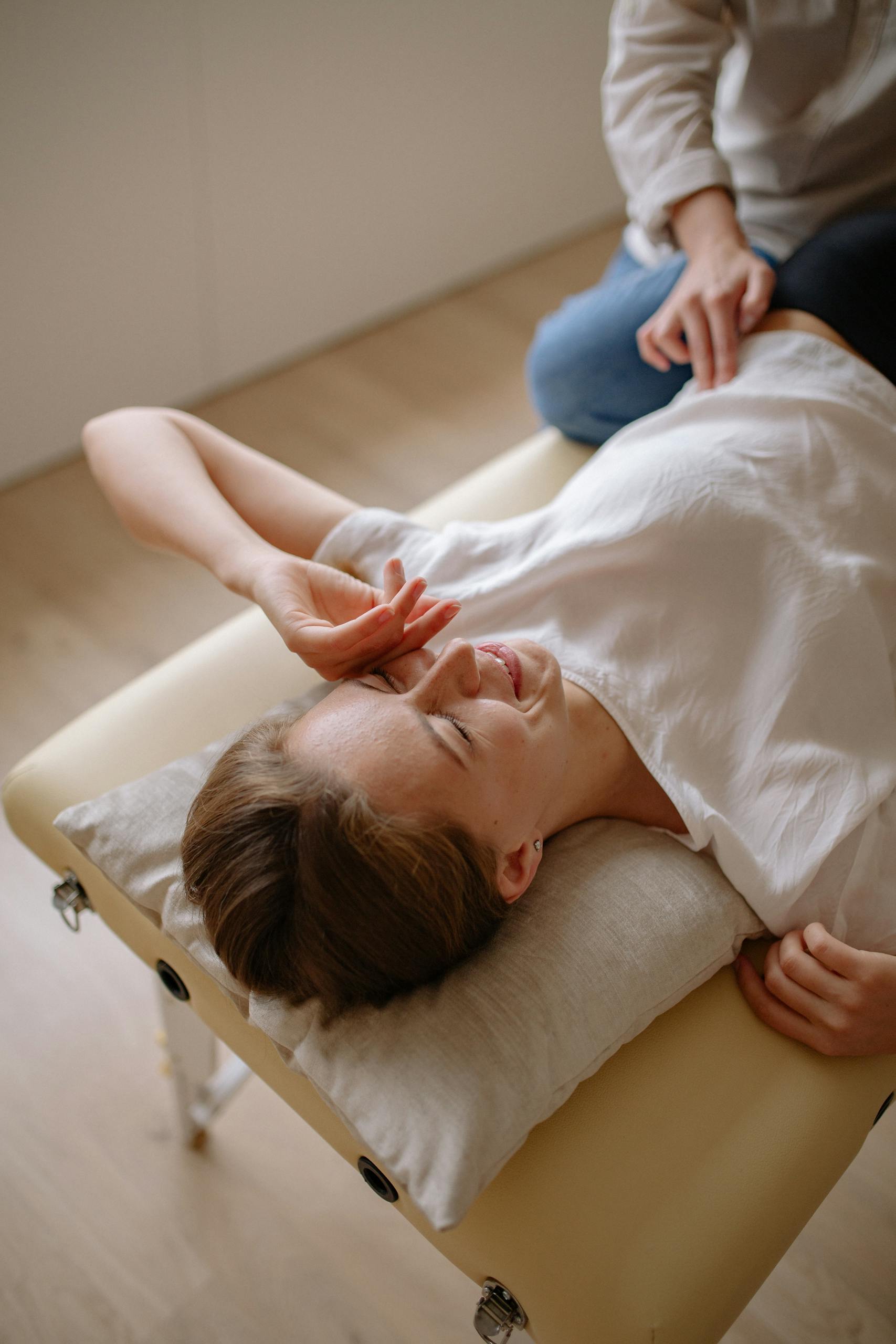 Woman lying on a therapy table, relaxing with eyes closed, receiving treatment.